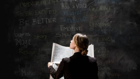 Businesswoman by blackboard holding newspaper